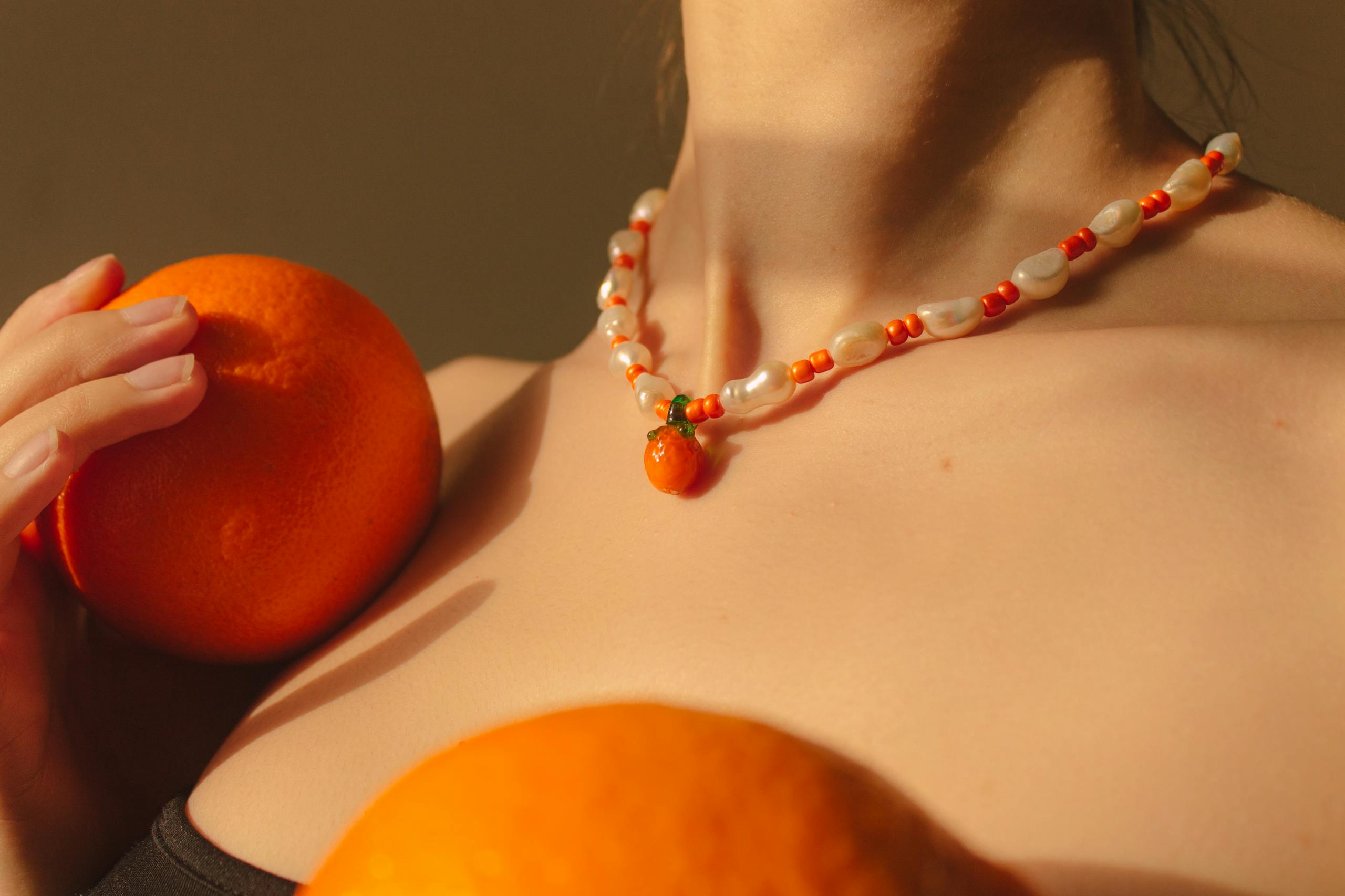 Close-up of a handmade necklace with oranges, showcasing fashion elegance.